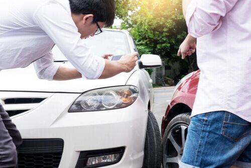 person taking pictures of car after auto accident