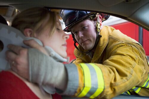 firefighter helping injured person in car